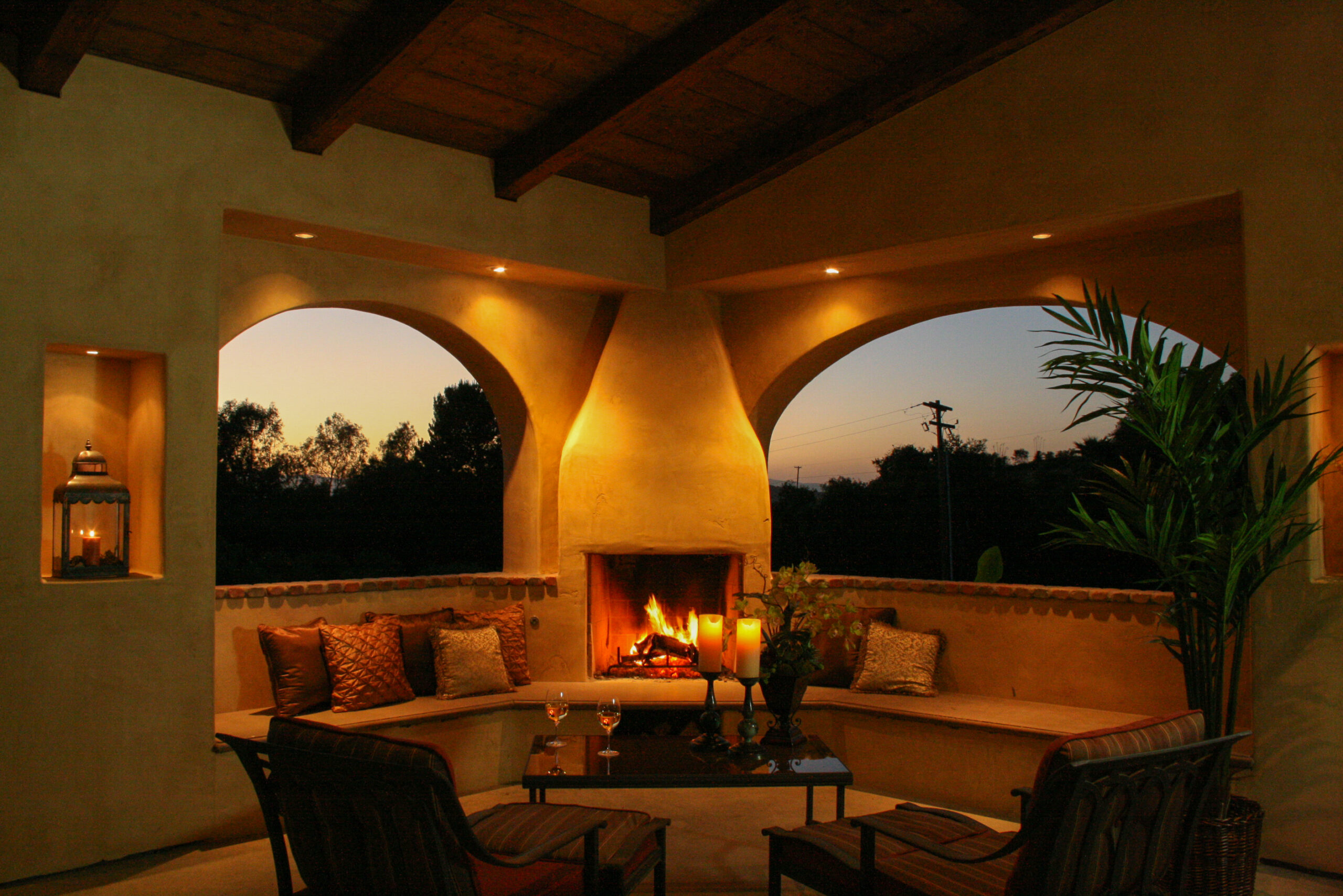 Outdoor lounge space with a wood fireplace and recessed can lights 