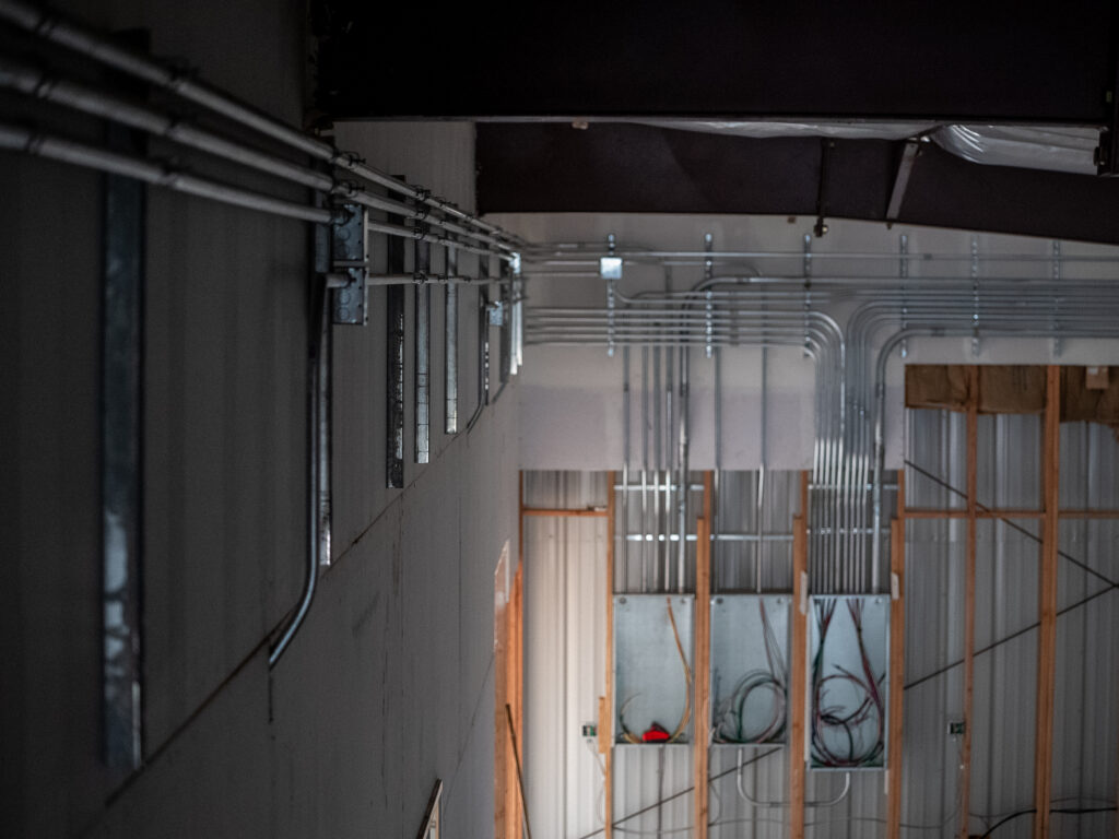 Industrial packing house with electrical conduit running along the walls into unfinished circuit breaker boxes. 