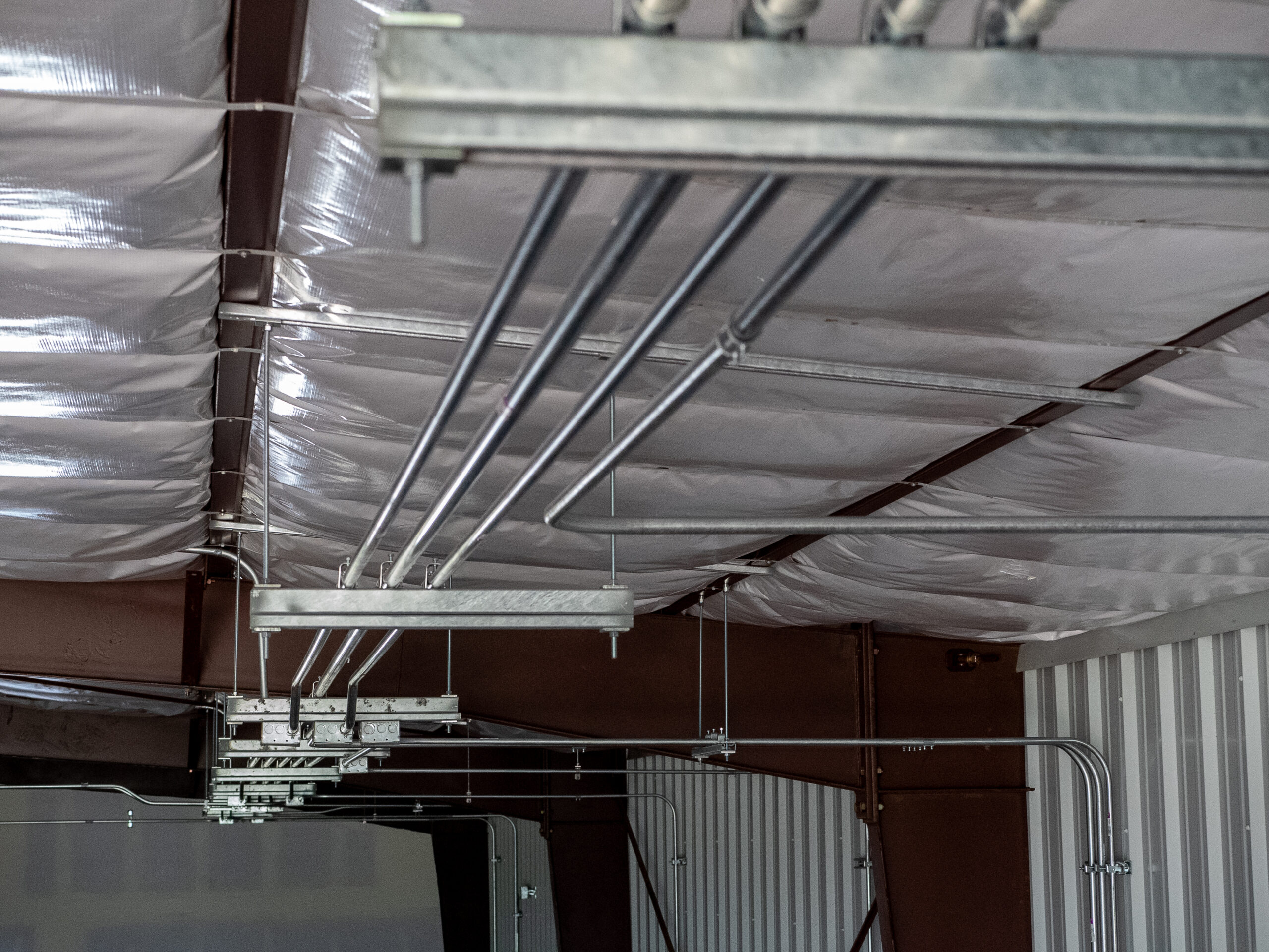 Electrical conduits running along a corrugated metal ceiling.